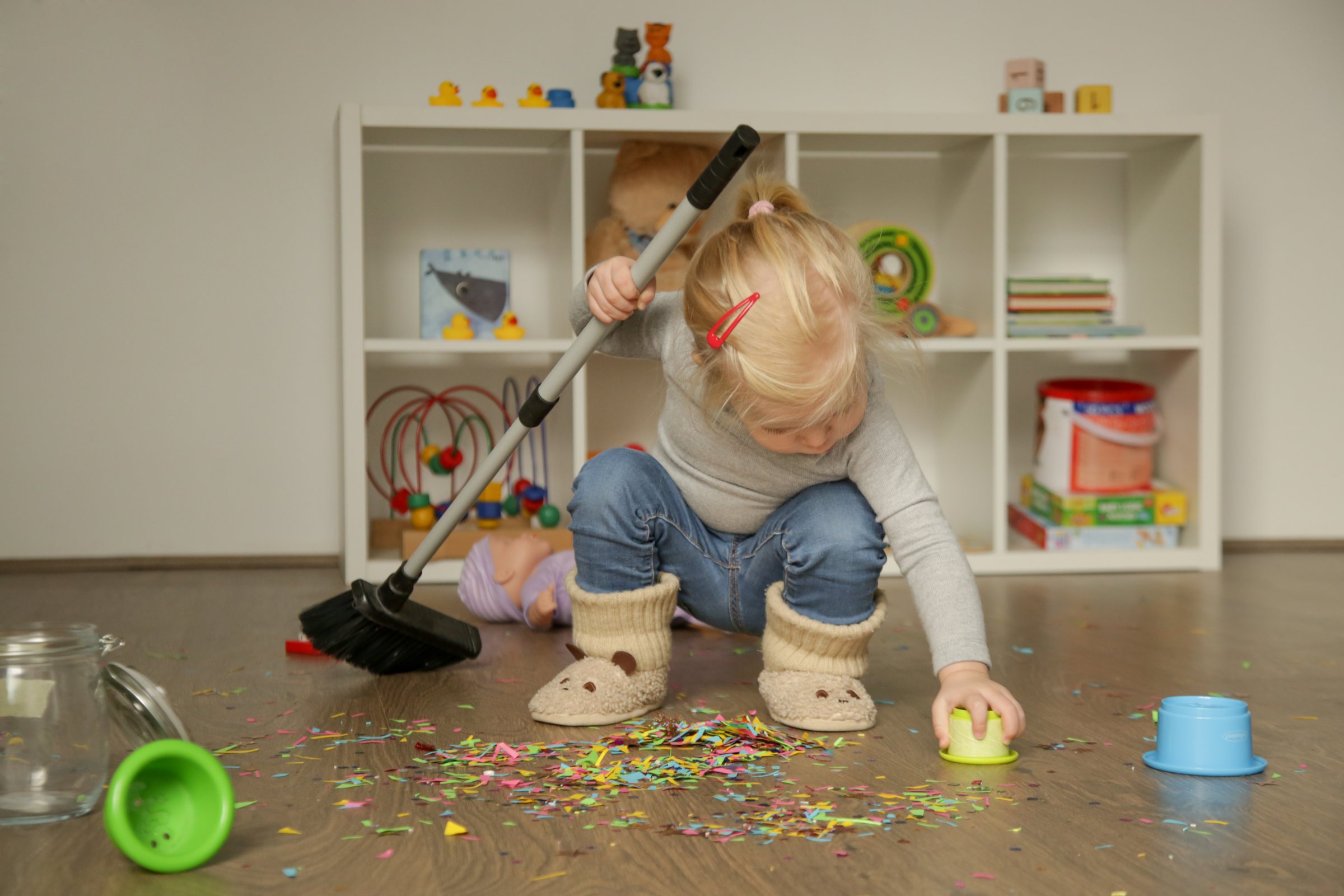 Toddler sweeping up with a child-sized broom