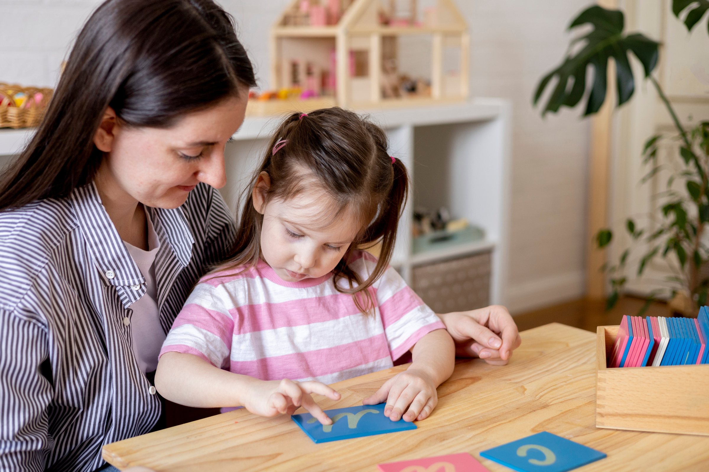 Educator guiding a child with sandpaper letters