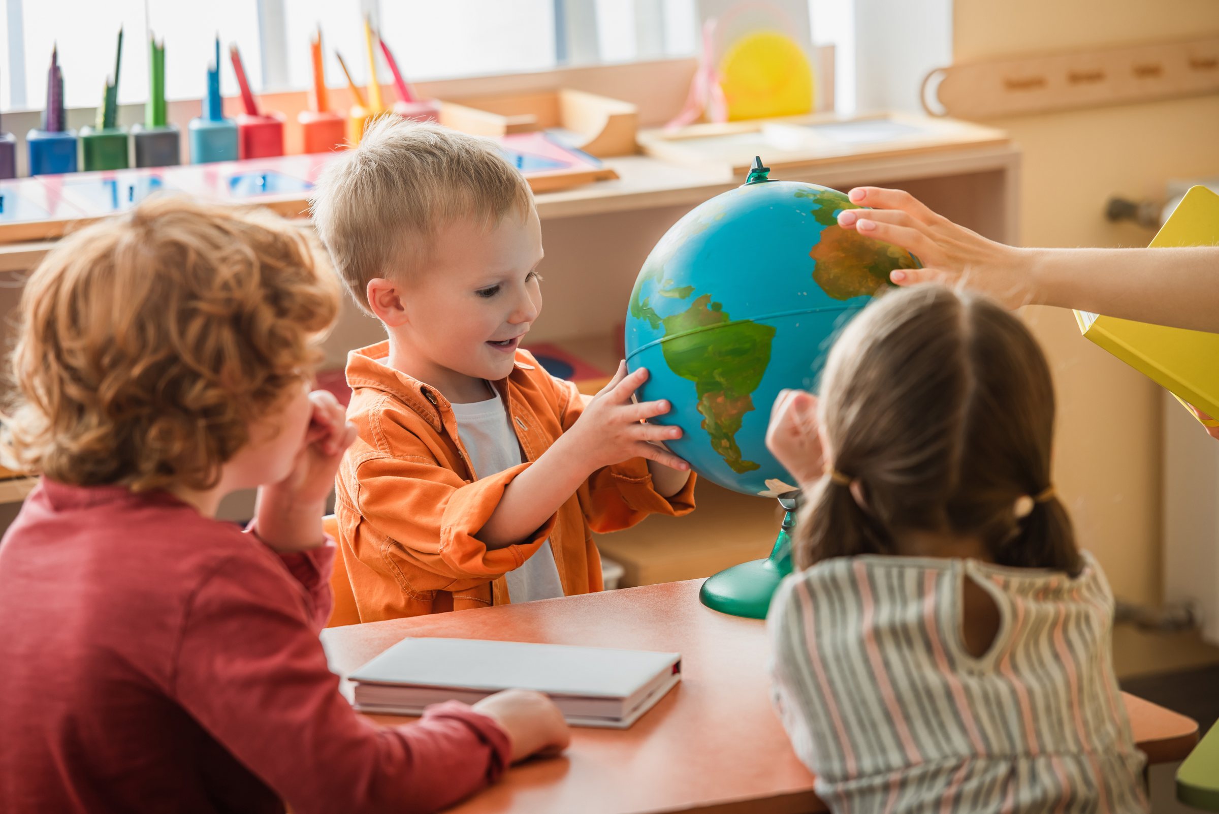 Preschoolers exploring a globe with their educator
