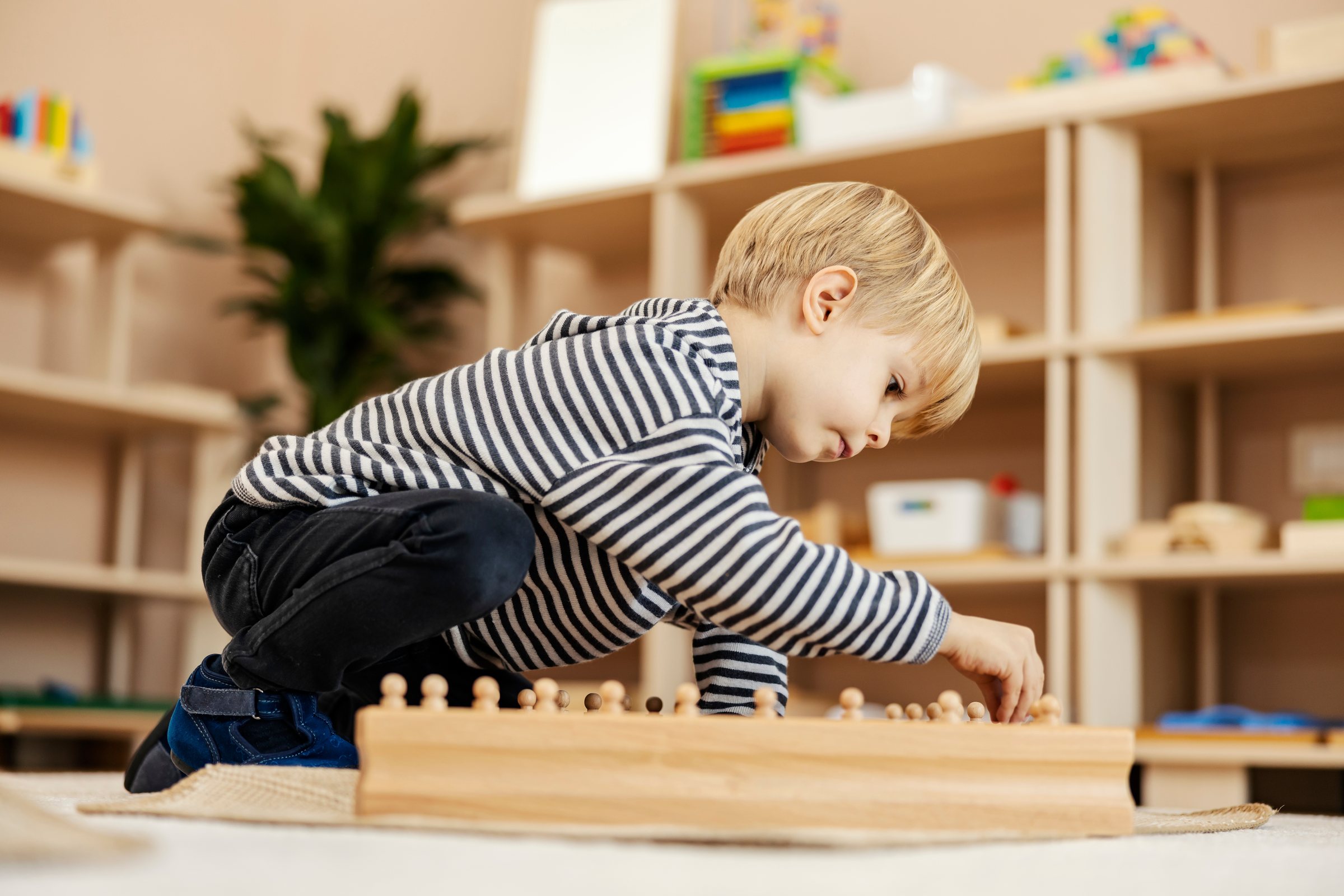 Boy concentrating on Montessori knobbed cylinders