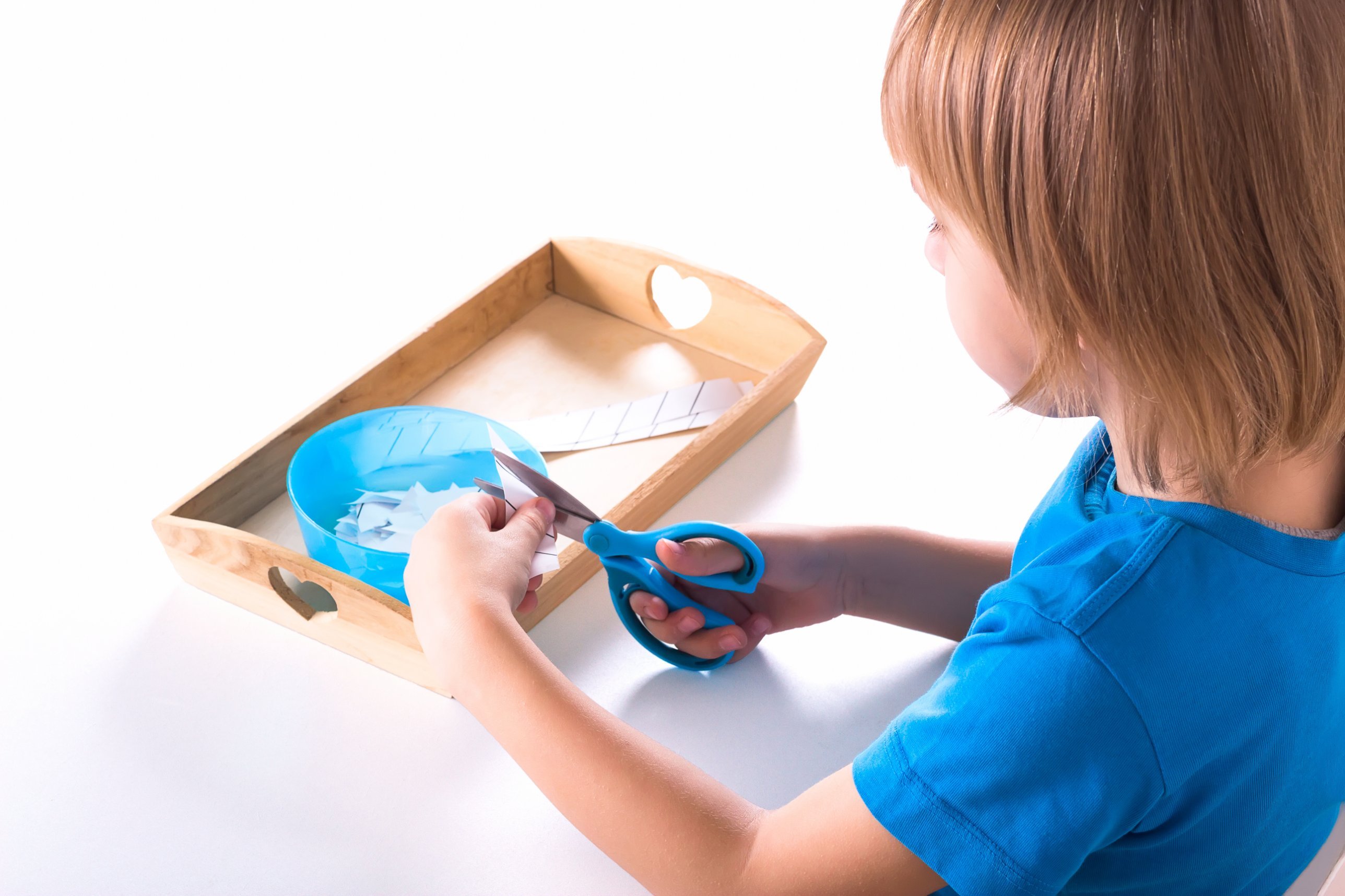 Child concentrating on a Montessori cutting tray