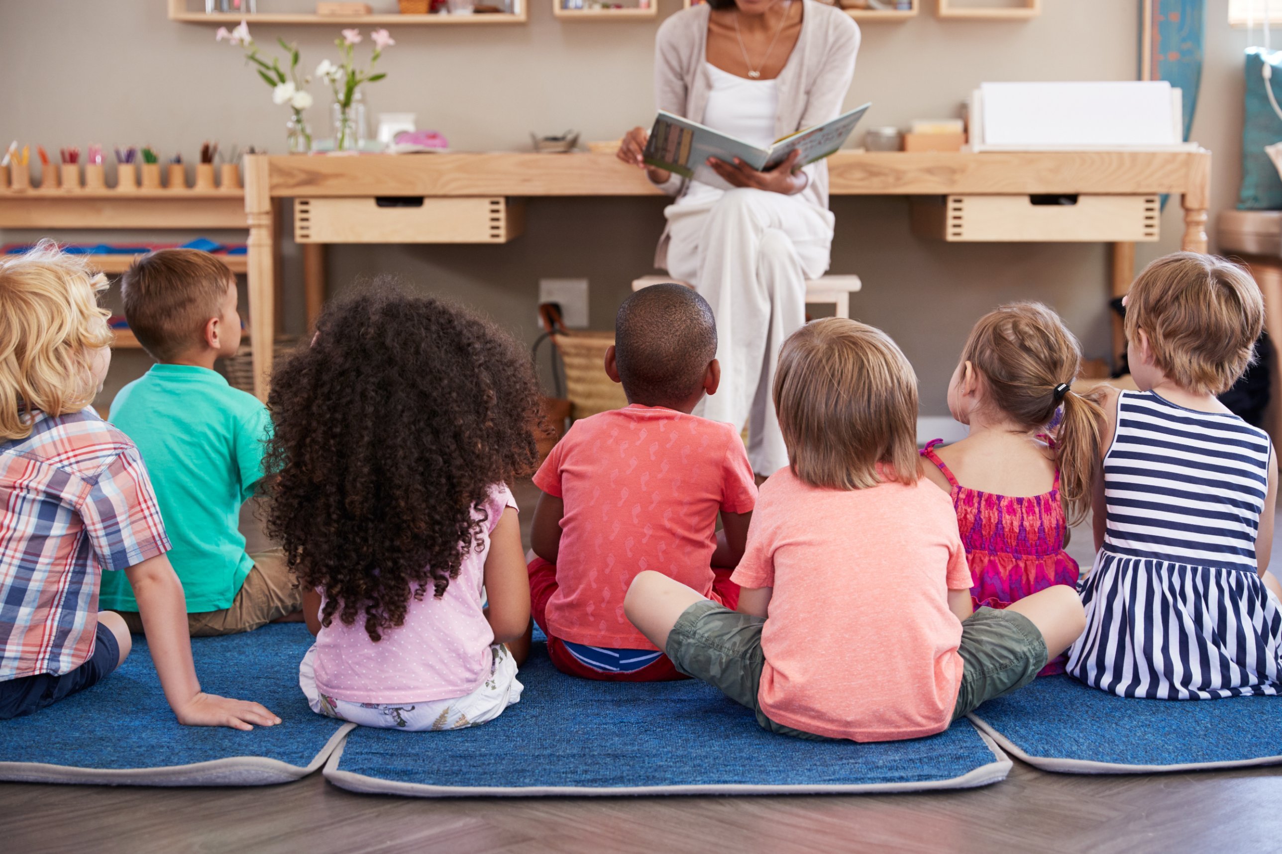 Preschoolers on the rug listening to their educator read a story
